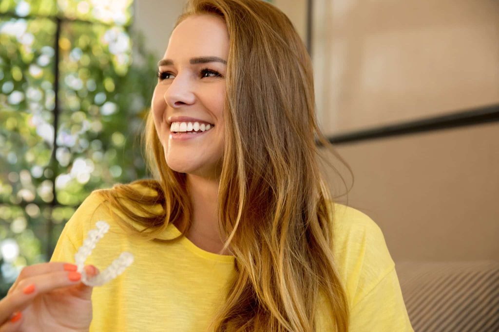 Lächelnde Patientin mit transparenter Invisalign-Aligner-Schiene
